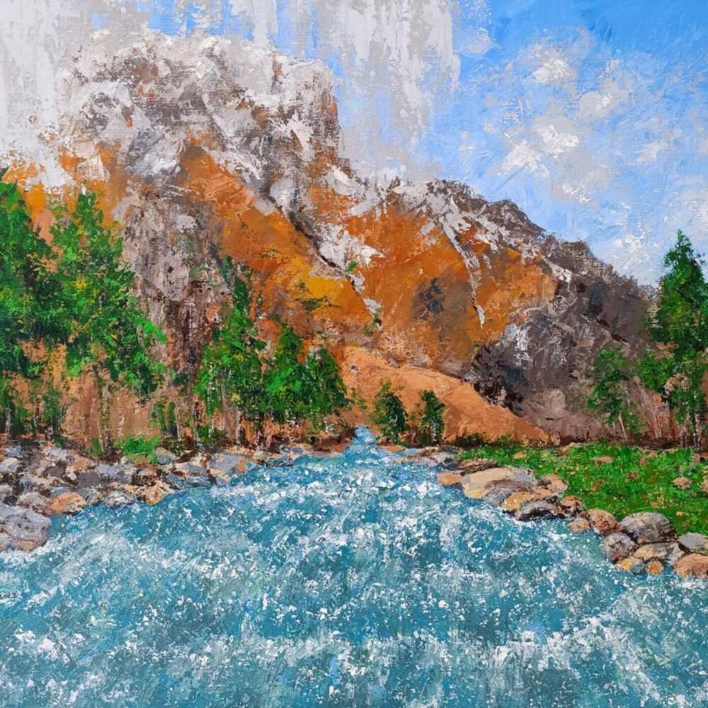 The Mountain River art print depicts a scenic landscape with a flowing river bordered by rocks, lush green trees along the banks, and towering mountains with snowy patches under a bright blue sky.