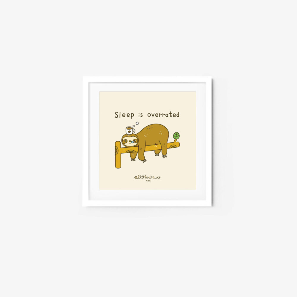The Sleep is overrated art print features a sloth asleep on a branch with a watching bird. The text above the sloth reads Sleep is overrated. The white frame contrasts with the soft beige background, adding charm to any space.