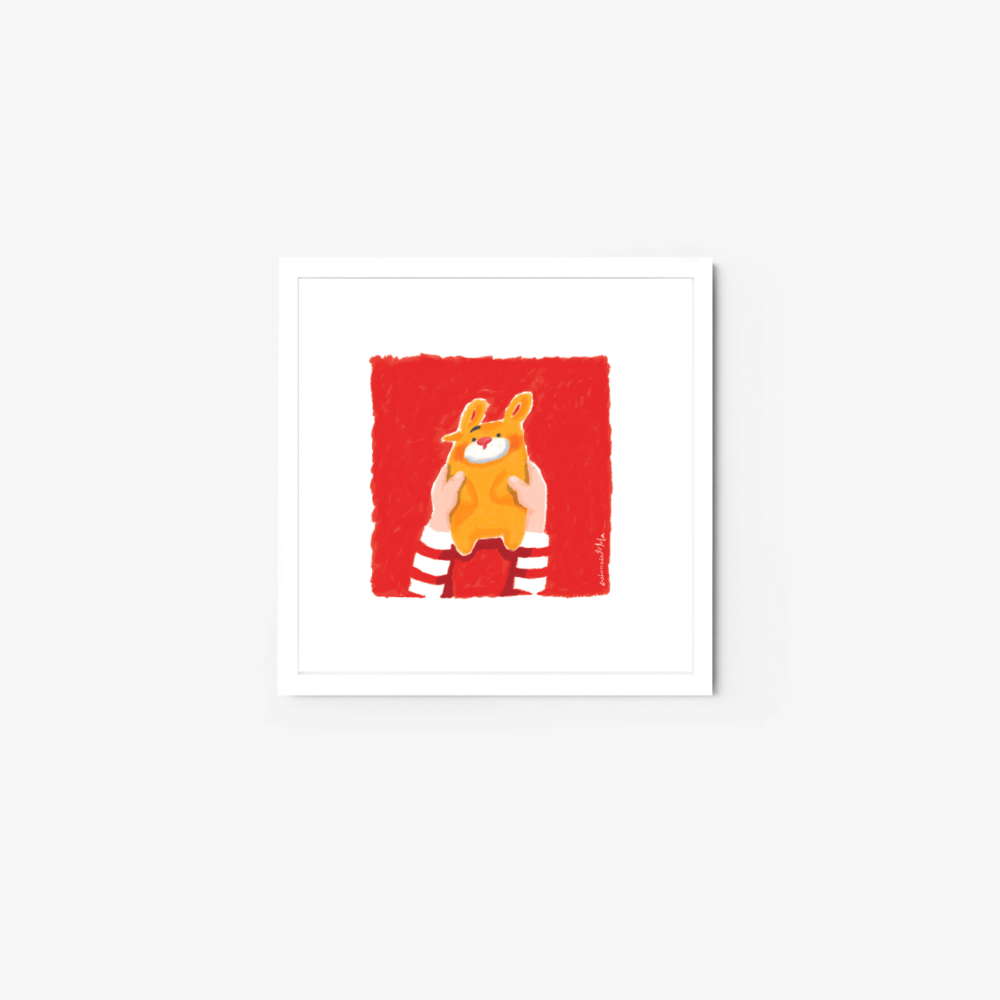 The framed art print Beary shows a person in a red and white striped shirt holding an orange rabbit plush against a solid red square backdrop. The frame is elegantly bordered in white, enhancing the whimsical illustrations charm.